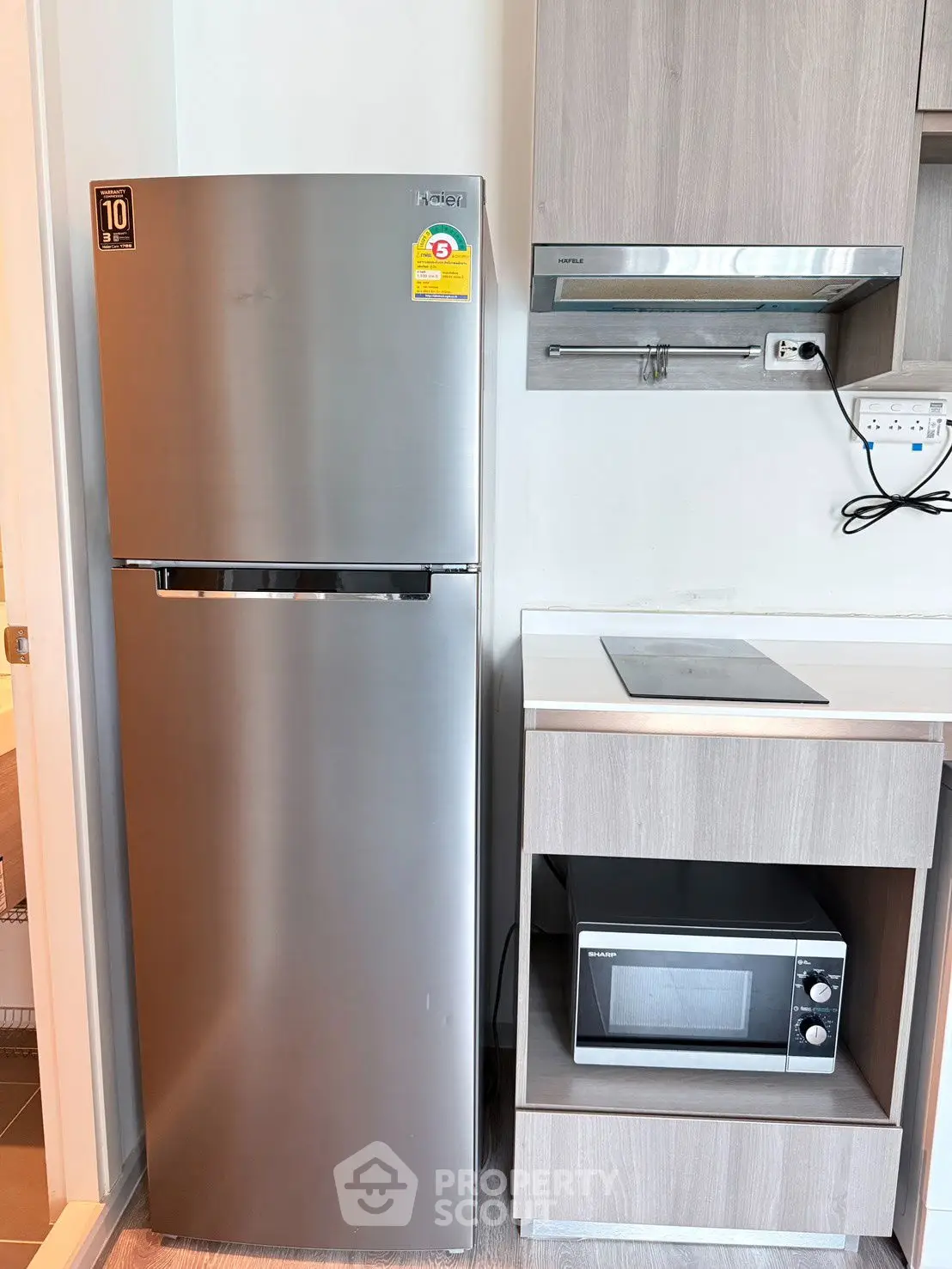 Modern kitchen with stainless steel fridge, microwave, and sleek cabinetry.