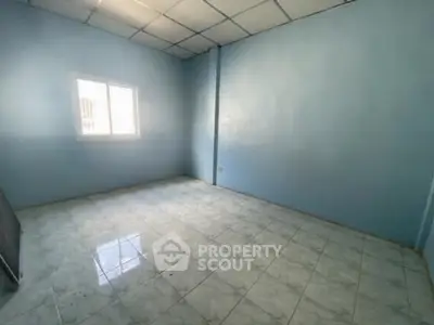 Spacious empty room with tiled floor and natural light from window