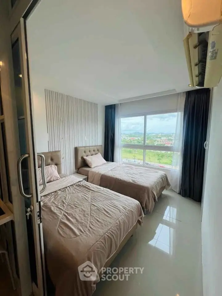 Modern bedroom with twin beds and large window offering scenic views.
