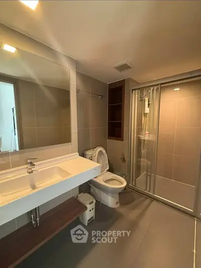 Modern bathroom with sleek fixtures and spacious shower in contemporary apartment.