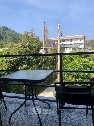 Charming balcony with scenic view of lush greenery and distant hills, perfect for relaxation.