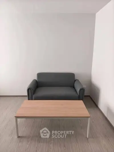 Minimalist living room with gray sofa and wooden coffee table on light wood flooring.