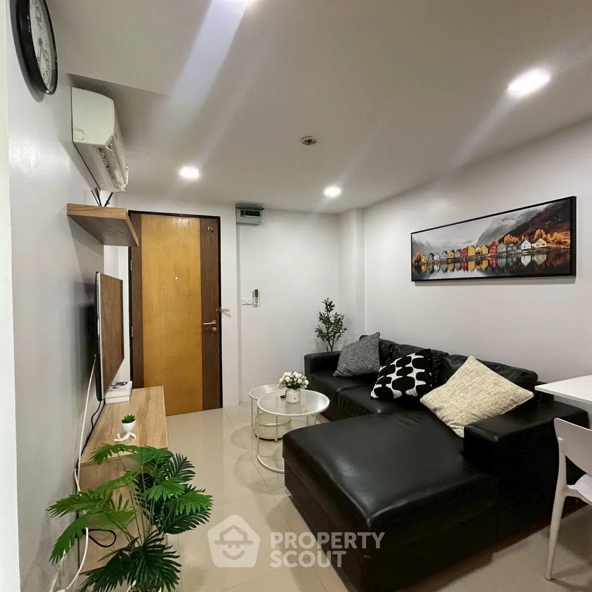 Modern living room with black sectional sofa and wall art, featuring sleek decor and ambient lighting.