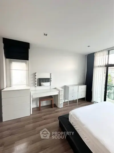 Spacious bedroom with modern furniture and large window for natural light.