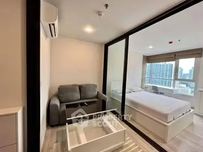 Modern studio apartment with glass partition, cozy living area, and city view.
