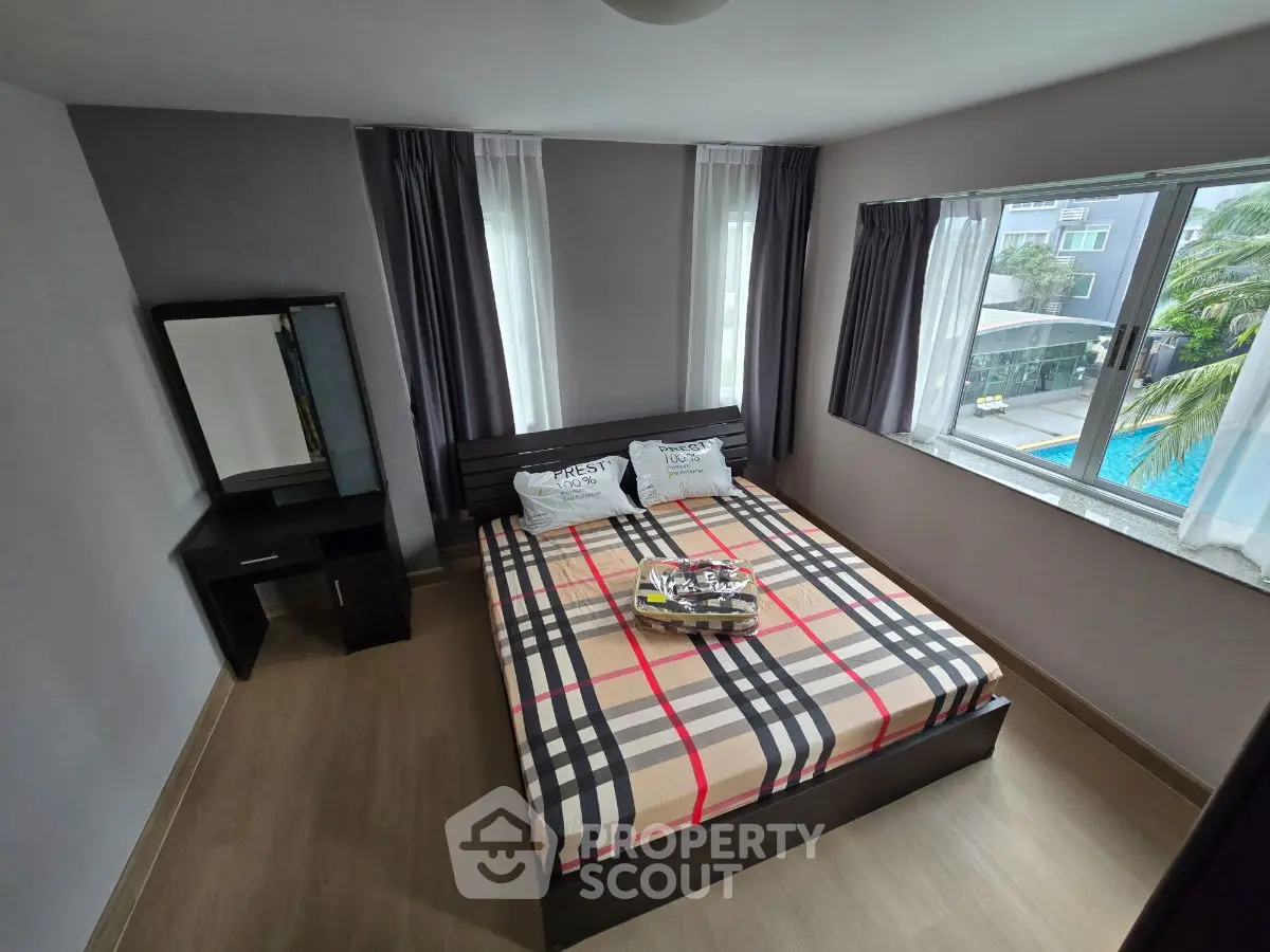 Modern bedroom with stylish decor and pool view, featuring a cozy bed and elegant vanity.