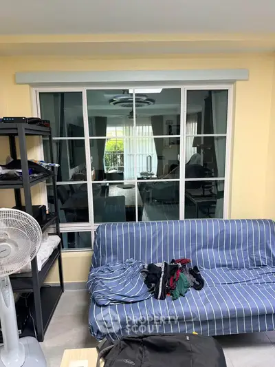 Cozy living room with large window and striped sofa, perfect for relaxation.