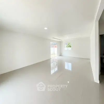 Spacious modern living room with glossy tiled floors and ample natural light.