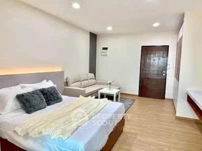 Spacious modern bedroom with cozy seating area and elegant decor