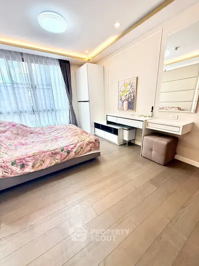 Elegant bedroom with floral bedding, modern furniture, and large window for natural light.