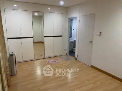Spacious bedroom with wooden flooring and mirrored wardrobe doors.