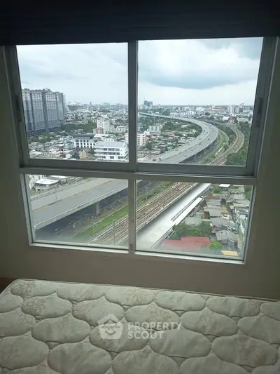 Stunning cityscape view from high-rise apartment window with highway and urban skyline.
