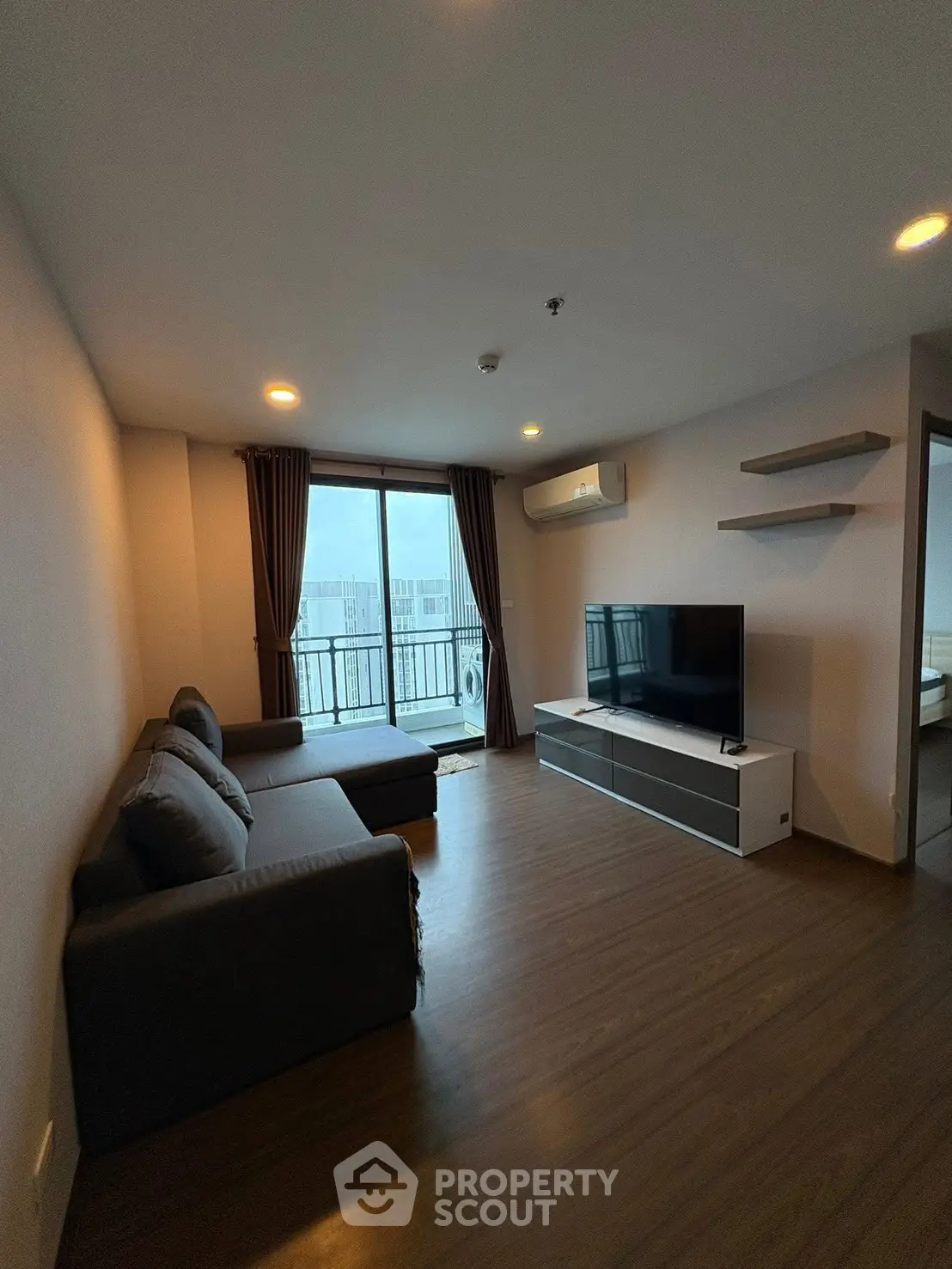 Modern living room with balcony view, featuring sleek furniture and ample natural light.
