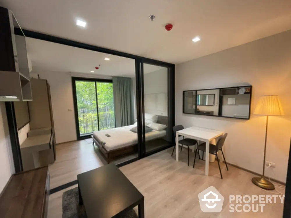 Modern studio apartment with glass partition, cozy bedroom, and stylish living area.