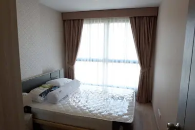 Cozy bedroom with large window and elegant curtains, perfect for relaxation and comfort.