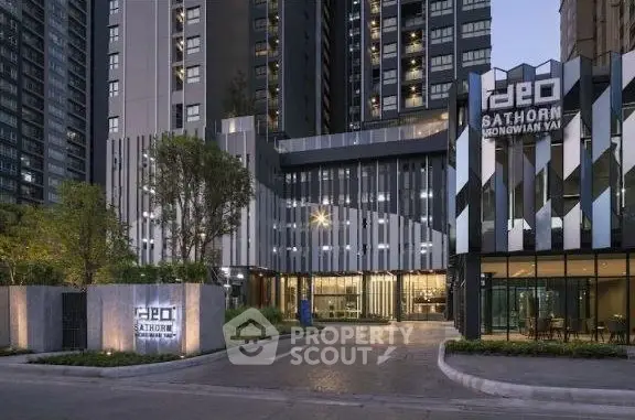 Modern high-rise building with sleek facade and entrance at dusk.
