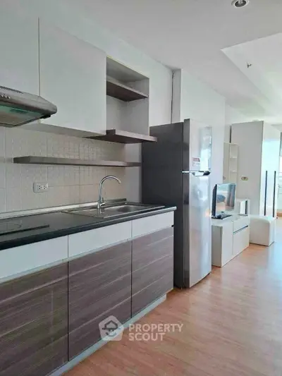 Modern kitchen with sleek cabinetry and stainless steel appliances in a bright open-plan apartment.