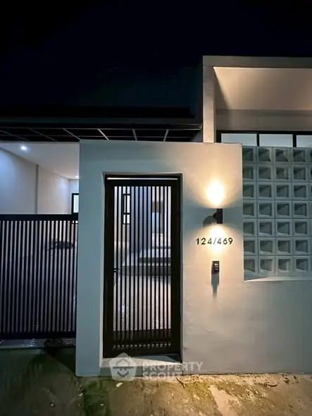 Modern house entrance with sleek gate and ambient lighting at night.