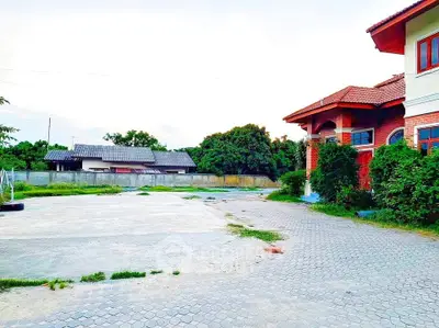 Spacious property with paved driveway and lush greenery, ideal for family living.