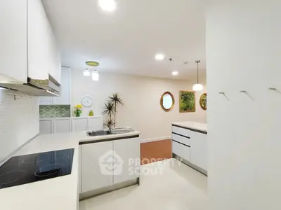 Modern kitchen with sleek white cabinets and island, featuring open layout and stylish decor.
