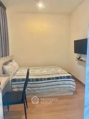 Cozy bedroom with modern decor and wall-mounted TV, perfect for relaxation.