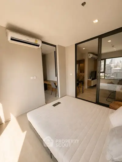 Modern bedroom with city view, featuring large windows and air conditioning unit, perfect for urban living.