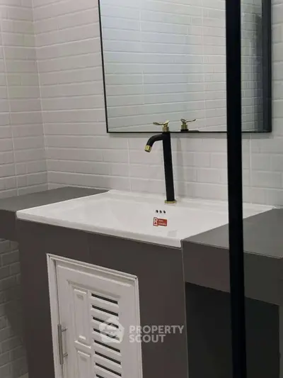 Modern bathroom with sleek sink and stylish black faucet, featuring elegant white tile backsplash.
