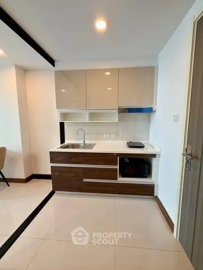 Modern compact kitchen with sleek cabinetry and integrated appliances in a stylish apartment.