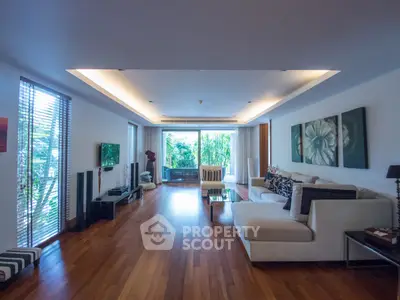 Spacious living room with modern decor and large windows overlooking lush greenery.