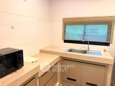 Modern kitchen with sleek countertops and built-in sink, featuring a microwave and window view.