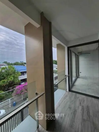 Spacious balcony with glass railing and scenic view of lush greenery.