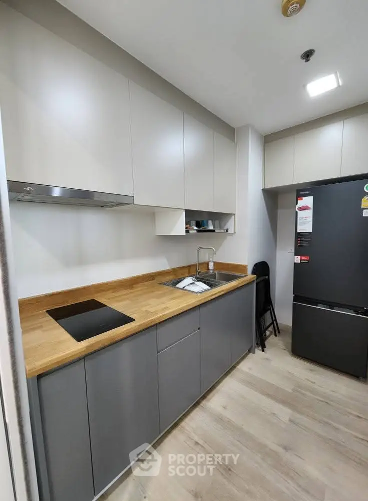 Modern kitchen with sleek cabinets and wooden countertop, featuring a compact design and integrated appliances.