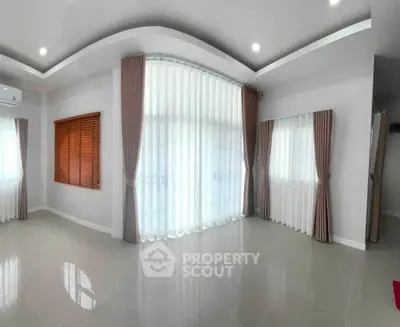 Spacious living room with elegant curtains and modern lighting, perfect for family gatherings.