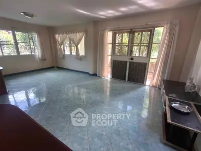 Spacious living room with large windows and tiled flooring in a bright home.