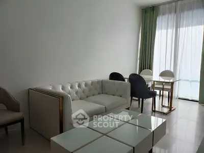 Modern living room with elegant white sofa and dining area, featuring floor-to-ceiling windows.