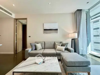 Modern living room with stylish gray sofa, chic decor, and large window offering natural light.