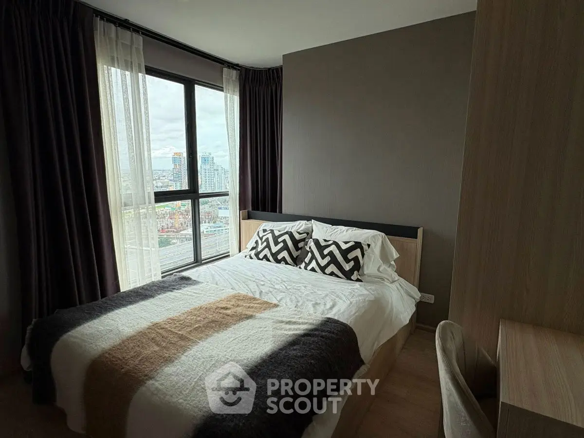 Cozy bedroom with city view, featuring modern decor and large windows for natural light.