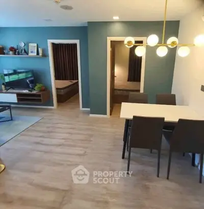 Modern living room with dining area and view into two bedrooms, featuring stylish lighting and decor.