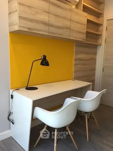 Modern study area with sleek desk and chairs, vibrant yellow accent wall, and stylish wooden cabinets.