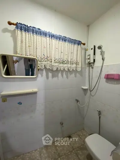 Cozy bathroom with shower and vintage curtain, ideal for compact living spaces.