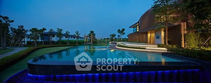 Luxurious modern home with stunning illuminated pool and lush landscaping at dusk.