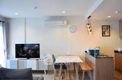 Modern living room with stylish decor and open kitchen layout, featuring a cozy dining area and sleek appliances.