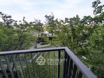 Scenic view from a balcony overlooking lush greenery and modern architecture.