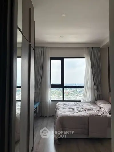 Modern bedroom with large window offering stunning city view and elegant decor.