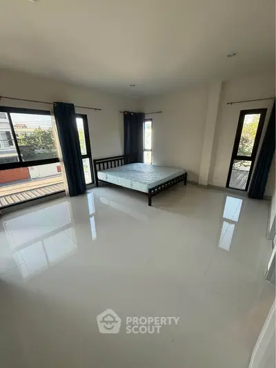 Spacious bedroom with large windows and minimalist decor in modern apartment