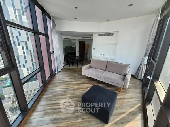 Spacious corner unit with floor-to-ceiling windows and modern furnishings in a high-rise building.