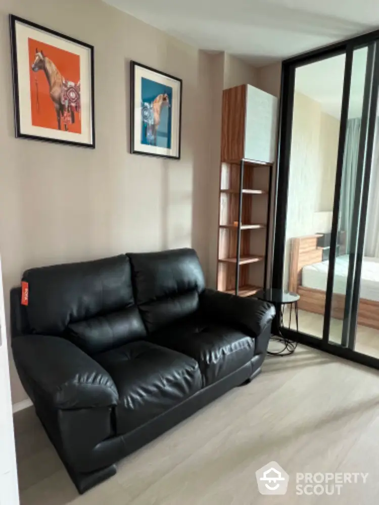 Modern living room with black leather sofa and stylish decor in a contemporary apartment.