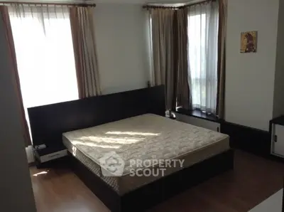 Spacious bedroom with large windows and modern furnishings, perfect for natural light lovers.