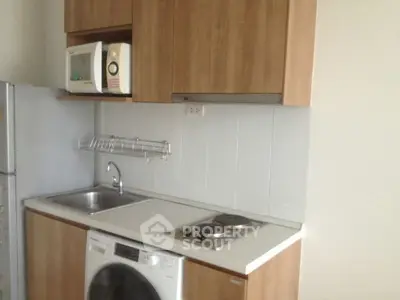 Compact kitchen with modern appliances and wooden cabinetry in a cozy apartment.