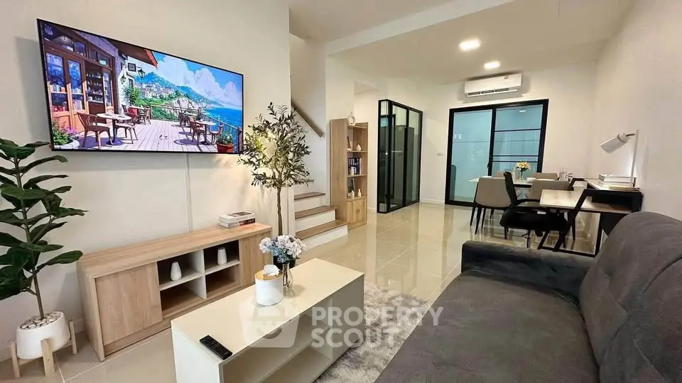 Modern living room with stylish decor, open layout, and large TV, perfect for relaxation and entertainment.